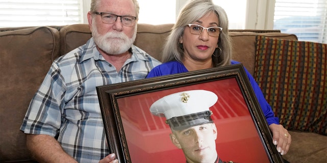 Joey and Paula Reed pose for a photo with a portrait of their son Marine veteran and Russian prisoner Trevor Reed at their home in Fort Worth, Texas, on Feb. 15, 2022.