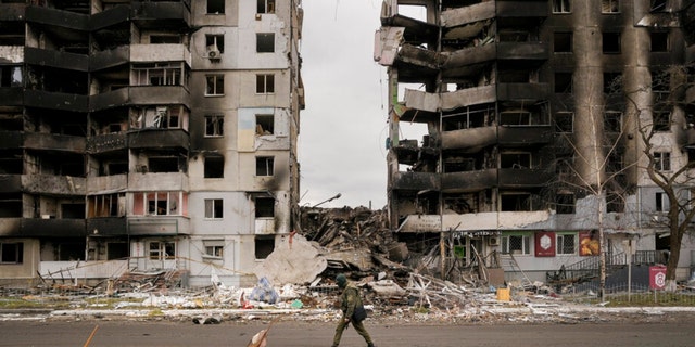 A Ukrainian serviceman walks by a destroyed apartment building in Borodyanka, Ukraine, Wednesday, April 6, 2022.