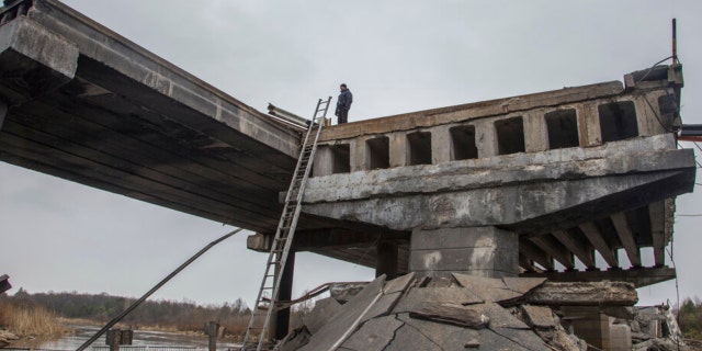 A Ukrainian serviceman stands on a destroyed bridge between the village of Dytiatky and Chernobyl, Ukraine, April 5, 2022.
