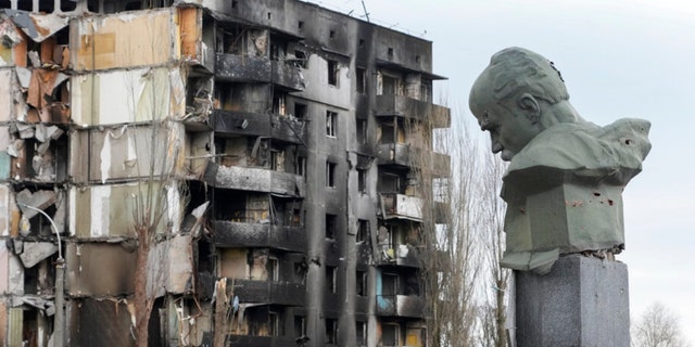 A monument to Taras Shevchenko, a Ukrainian poet and national symbol, is seen with bullet marks against the backdrop of a building ruined in the Russian bombardment in the central square of Borodyanka, Ukraine, Wednesday, April 6, 2022.