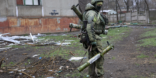 
An armed serviceman of Donetsk People's Republic militia walks past a building damaged during fighting in Mariupol on Wednesday.