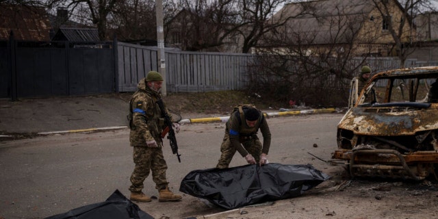 Ukrainian soldiers recover the remains of four killed civilians from inside a charred vehicle in Bucha, outskirts of Kyiv, Ukraine, Tuesday, April 5, 2022. 