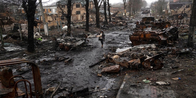 A woman walks amid destroyed Russian tanks in Bucha, in the outskirts of Kyiv, Ukraine, Sunday, April 3, 2022.