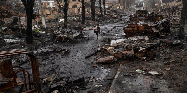 A woman walks amid destroyed Russian tanks in Bucha, in the outskirts of Kyiv, Ukraine, Sunday, April 3, 2022.