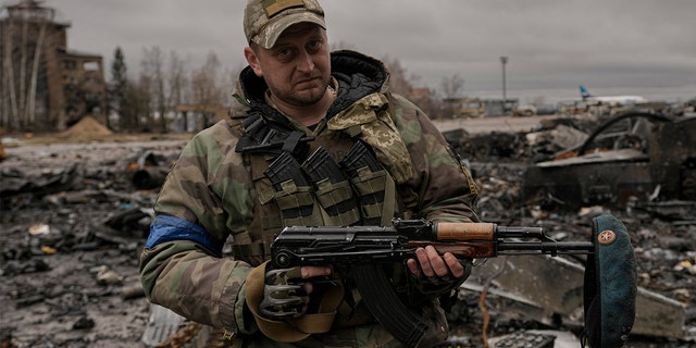 A Ukrainian serviceman poses with a Russian beret he retrieved from a destroyed Russian military vehicle on his weapon at the Antonov airport in Hostomel, Ukraine, April 2, 2022.  