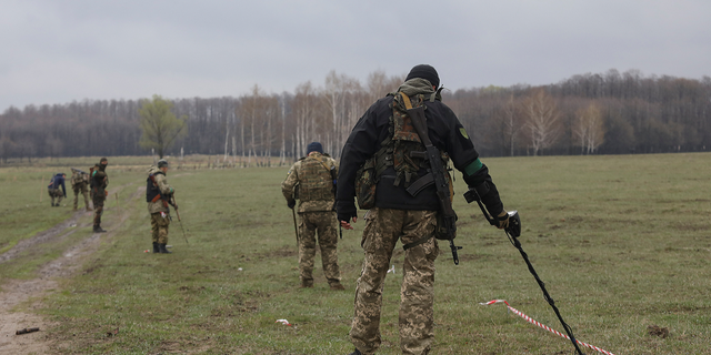 The Ukrainian military inspects an area for mines and non-exploded shells left after Russia's invasion in the Kyiv region on Thursday, April 21.