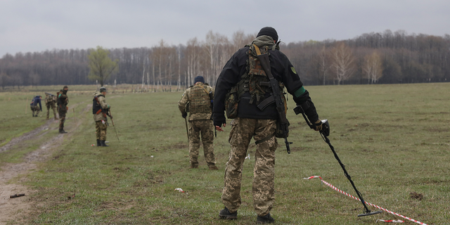 The Ukrainian military inspects an area for mines and non-exploded shells left after Russia's invasion in the Kyiv region on Thursday, April 21.