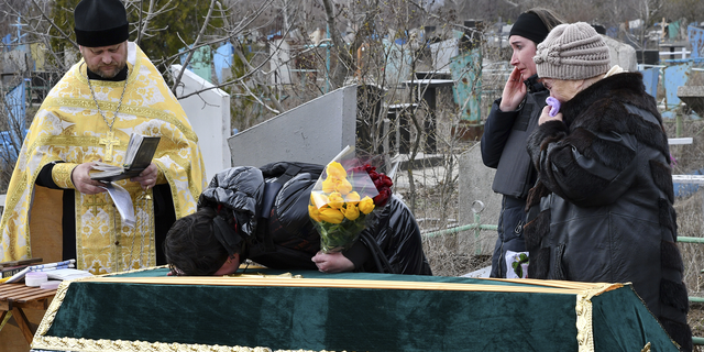 Relatives and friends stand near the coffin of Ukrainian serviceman Anatoly German during a funeral ceremony in Kramatorsk, Ukraine, on Tuesday. Anatoly German was killed during fightings between Russian and Ukrainian forces near the city of Severodonetsk. He leaves a wife, daughter Adelina, 9, son Kirill, 3. 
