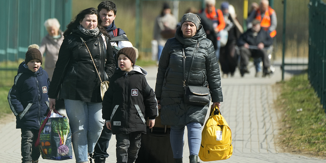 لاجئون يمشون بعد فرارهم من الحرب من أوكرانيا المجاورة عند المعبر الحدودي في ميديكا ، جنوب شرق بولندا ، في 8 أبريل 2022.