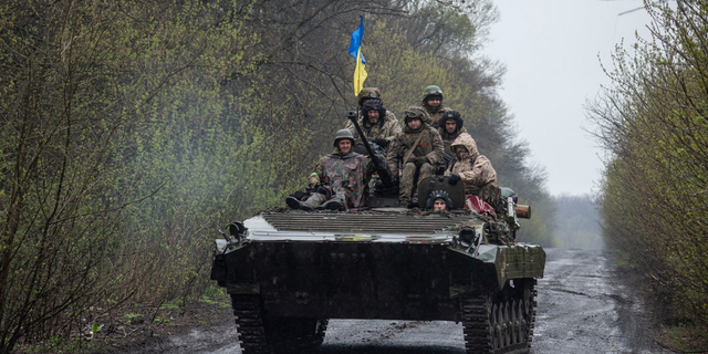Ukrainian servicemen ride atop an armored fighting vehicle at an unknown location in Eastern Ukraine.