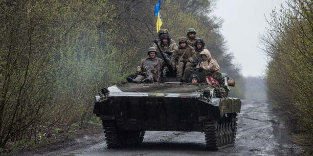 Ukrainian servicemen ride atop an armored fighting vehicle at an unknown location in Eastern Ukraine.