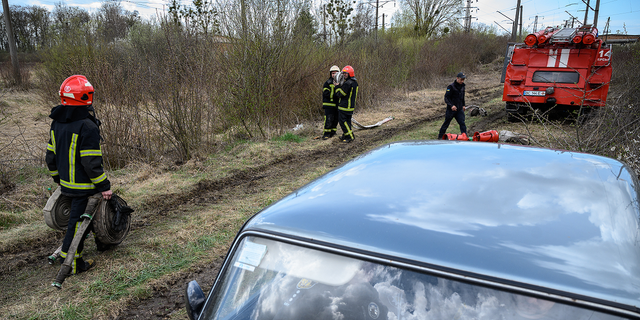 Firefighters carry hoses near the location of a missile strike on April 25, 2022 near Lviv, Ukraine.
