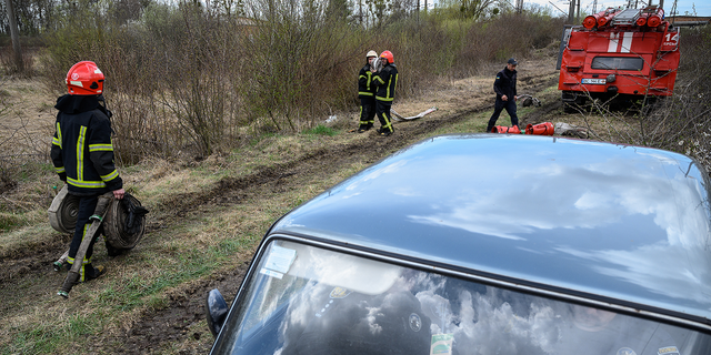 Firefighters carry hoses near the location of a missile strike on April 25, 2022 near Lviv, Ukraine.