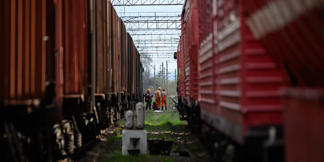 Rail workers wait between two train lines near the site of a missile strike near Lviv, Ukraine, on April 25, 2022.