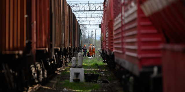 Railway workers wait between two train lines near the site of a missile strike near Lviv, Ukraine, April 25, 2022.