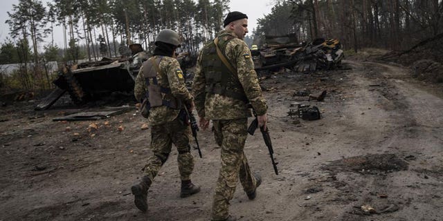 Ukrainian soldiers walking next to destroyed Russian tanks in the outskirts of Kyiv, Ukraine, March 31.