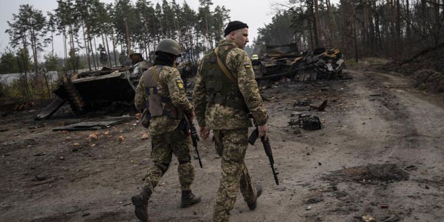 Ukrainian soldiers walk next to destroyed Russian tanks on the outskirts of kyiv, Ukraine, Thursday, March 31, 2022.