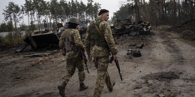 Ukrainian soldiers walking next to destroyed Russian tanks in the outskirts of Kyiv, Ukraine, March 31.