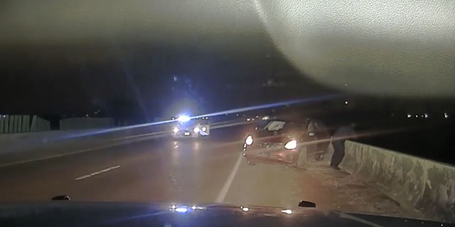 A law enforcement officer leaned over a bridge after a man jumped near Memphis, Tennessee, after a police chase April 17, 2022, in this image from video released by the West Memphis Police Department.