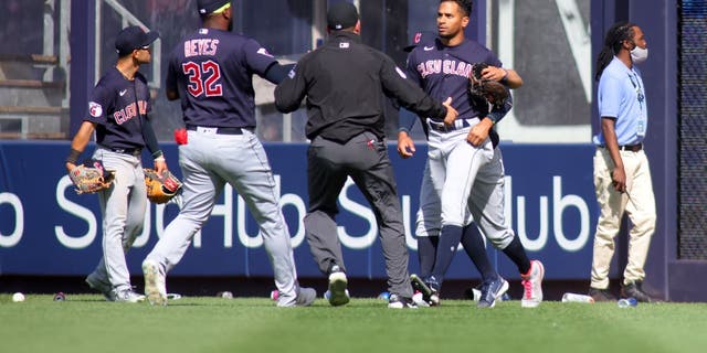 APRIL 23: Oscar Mercado #35 of the Cleveland Guardians is restrained as fans throw debris on the field following Gleyber Torres #25 of the New York Yankees walk off RBI single in the bottom of the ninth inning at Yankee Stadium on April 23, 2022 in New York City. 