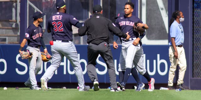 Yankees fans hurl trash at Guardians players 3 APRIL 23: Oscar Mercado #35 of the Cleveland Guardians is restrained as fans throw debris on the field following Gleyber Torres #25 of the New York Yankees walk off RBI single in the bottom of the ninth inning at Yankee Stadium on April 23, 2022 in New York City.