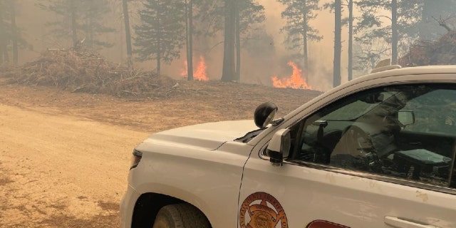 A Yavapai County Sheriff's Office car and flames on the side of a road