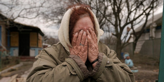 Tetiana Oleksiienko cries as she stands at the gate of her house in the village of Andriivka, Ukraine, which was heavily affected by fighting between Russian and Ukrainian forces, on Wednesday, April 6, 2022. 