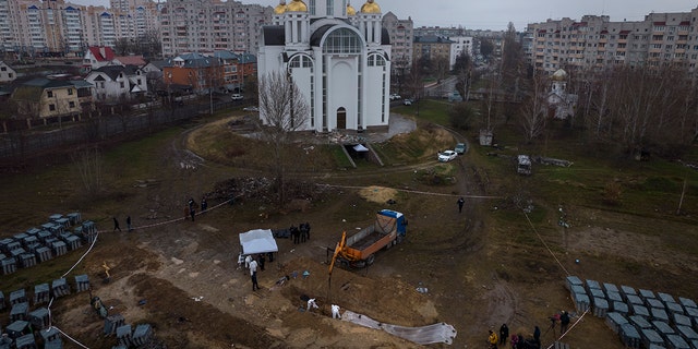 I lavoratori del cimitero lavorano in una fossa comune a Bucha, alla periferia di Kiev, in Ucraina, per identificare i civili uccisi durante la guerra contro la Russia, domenica 10 aprile 2022.