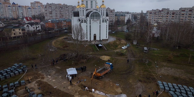 I lavoratori del cimitero lavorano in una fossa comune a Bucha, alla periferia di Kiev, in Ucraina, per identificare i civili uccisi durante la guerra contro la Russia, domenica 10 aprile 2022.