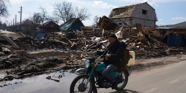A man rides a motorbike past a house damaged by shelling in Chernihiv, Ukraine, Thursday, April 7, 2022. (AP Photo/Evgeniy Maloletka) 