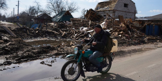 A man rides a motorbike past a house damaged by shelling in Chernihiv, Ukraine, Thursday, April 7, 2022. (AP Photo/Evgeniy Maloletka)