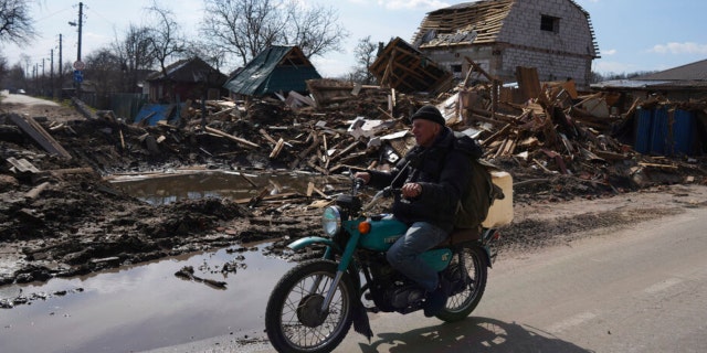 A man rides a motorbike past a house damaged by shelling in Chernihiv, Ukraine, Thursday, April 7, 2022. (AP Photo/Evgeniy Maloletka) 