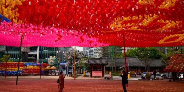 Visitors wearing face masks to help curb the spread of the coronavirus take a photograph under lanterns ahead of the upcoming birthday of Buddha on May 8, at the Jogye temple in Seoul, South Korea, Thursday, April 21, 2022.