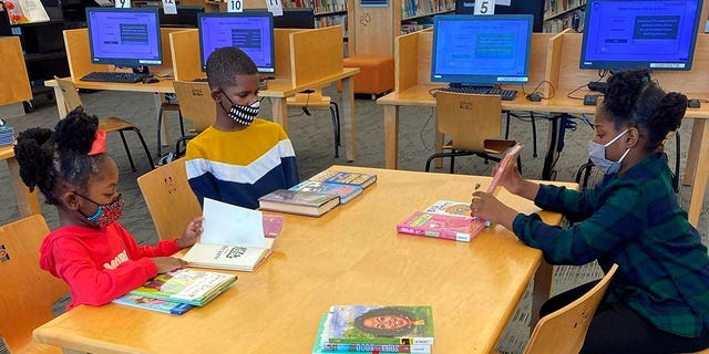 Drew Waller, 7, Ahmad Waller, 11, and Zion Waller, 10, left to right, study at Cameron Village Library during homeschooling, in Raleigh, North Carolina.