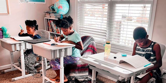 Dalaine Bradley, Drew Waller, 7, Zion Waller, 10, and Ahmad Waller, 11, left to right, study during homeschooling, in Raleigh, North Carolina.