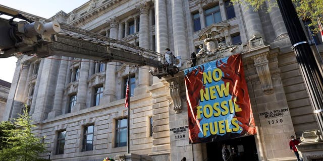 The fire department uses a ladder truck to remove environmental activists after they scaled the Wilson Building as part of an Earth Day rally against fossil fuels on April 22, 2022, in Washington, D.C.