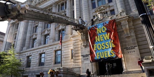 The fire department uses a ladder truck to remove an environmental activists with the group Extinction Rebellion DC after they scaled the Wilson Building as part of an Earth Day rally against fossil fuels on April 22, 2022 in Washington, D.C.