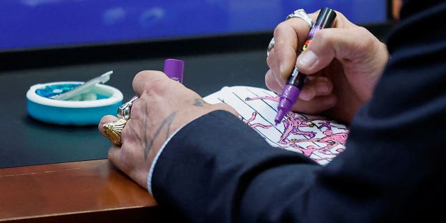 Actor Johnny Depp draws in a sketch pad during his defamation trial against ex-wife Amber Heard at the Fairfax County Circuit Courthouse in Fairfax, Va., April 27, 2022.