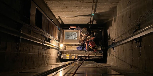 Two firefighters rappelled down the elevator shaft to rescue six children trapped inside a stuck elevator.