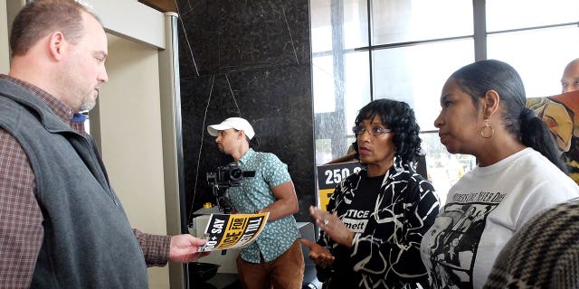 Deborah Watts, second from right, a cousin of Emmett Till, hands Mississippi Attorney General Office representative Wayne Lynch a poster and thumb drive that allegedly has almost 300,000 signatures on a petition seeking a renewed probe of the 1955 lynching, in Jackson, Mississippi, on March 11, 2022.