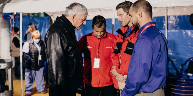Rev. Franklin Graham (at left) is shown praying with a team of volunteers on the ground in Ukraine during an April 2022 trip to the war-torn country.