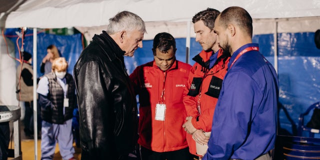 Rev. Graham (at left), is shown praying with a team on the ground in Ukraine.