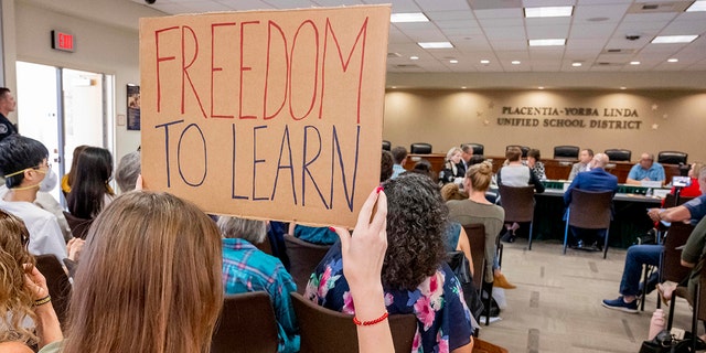PLACENTIA, CA - MARCH 23: A student holds up a sign against banning CRT holds up a sign as members of the Placentia-Yorba Linda Unified School Board meet in Placentia on Wednesday, March 23, 2022.
