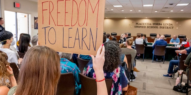 A student holds up a sign against banning CRT holds up a sign as members of the Placentia-Yorba Linda Unified School Board meet in Placentia on Wednesday, March 23, 2022, to consider banning the academic concept of critical race theory in the district. 