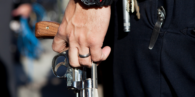 A police officer carries a Smith and Wesson revolver during a gun buy-back, Dec. 21, 2012, in San Diego, California.