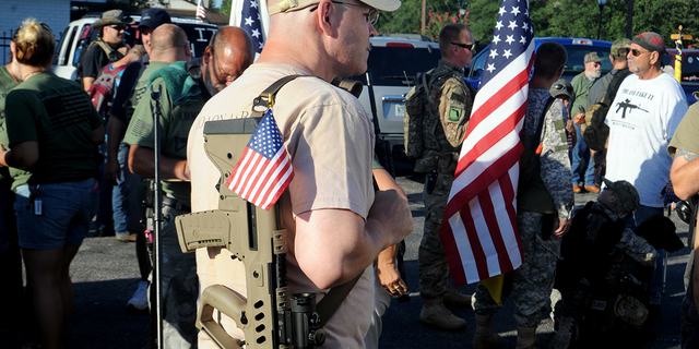 With loaded firearms in hand and flags all around, people gather for a 5-Mile Open Carry March for Freedom organized by Florida Gun Supply in Inverness, Fla. luglio 4, 2016. 