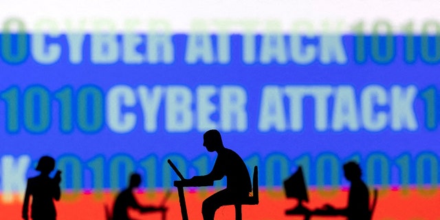 Figurines with computers and smartphones are seen in front of the words "Cyber Attack," binary codes and the Russian flag, in this illustration taken February 15, 2022. 