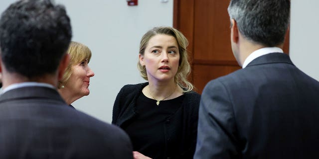 Actress Amber Heard speaks to her legal team in the courtroom of Fairfax County Courthouse in Fairfax, Virginia, Thursday, April 28, 2022. Actor Johnny Depp sued his ex-wife, actress Amber Heard, for defamation in Fairfax County Court after she did so.  She wrote an op-ed in the Washington Post in 2018 referring to herself as a "A public figure representing domestic violence." 