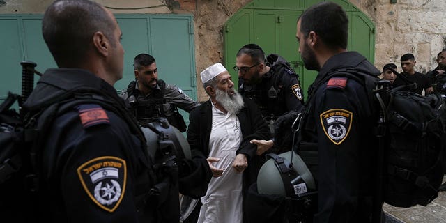 Israel police officers argue with a Palestinian worshiper in the Old City of Jerusalem, Sunday, April 17, 2022.