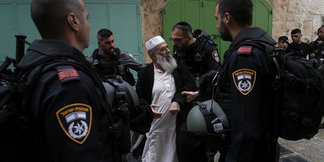 Israeli police argue with a Palestinian worshiper in the Old City of Jerusalem on April 17, 2022.